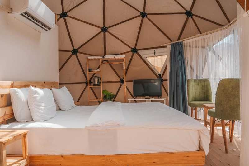 Geodesic dome interior with comfortable bed and modern amenities at Willow Garth