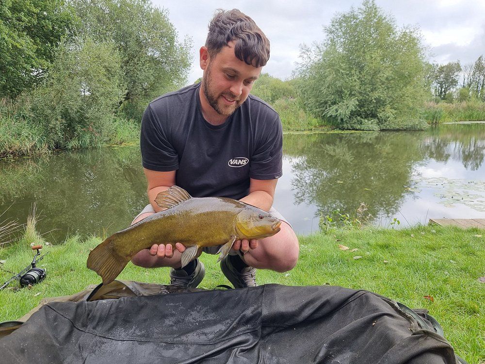 Angler with tench by the lake